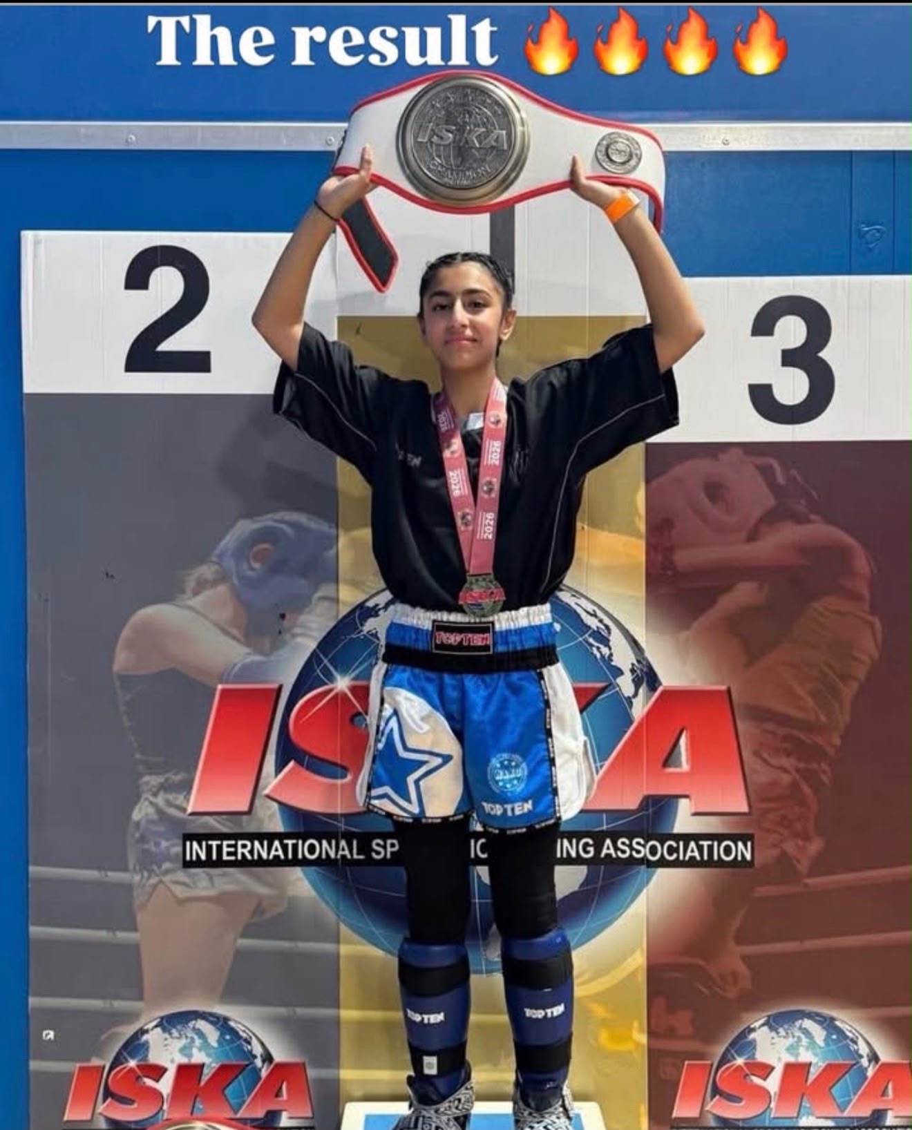 A young fighter lifts her ISKA championship belt on the podium